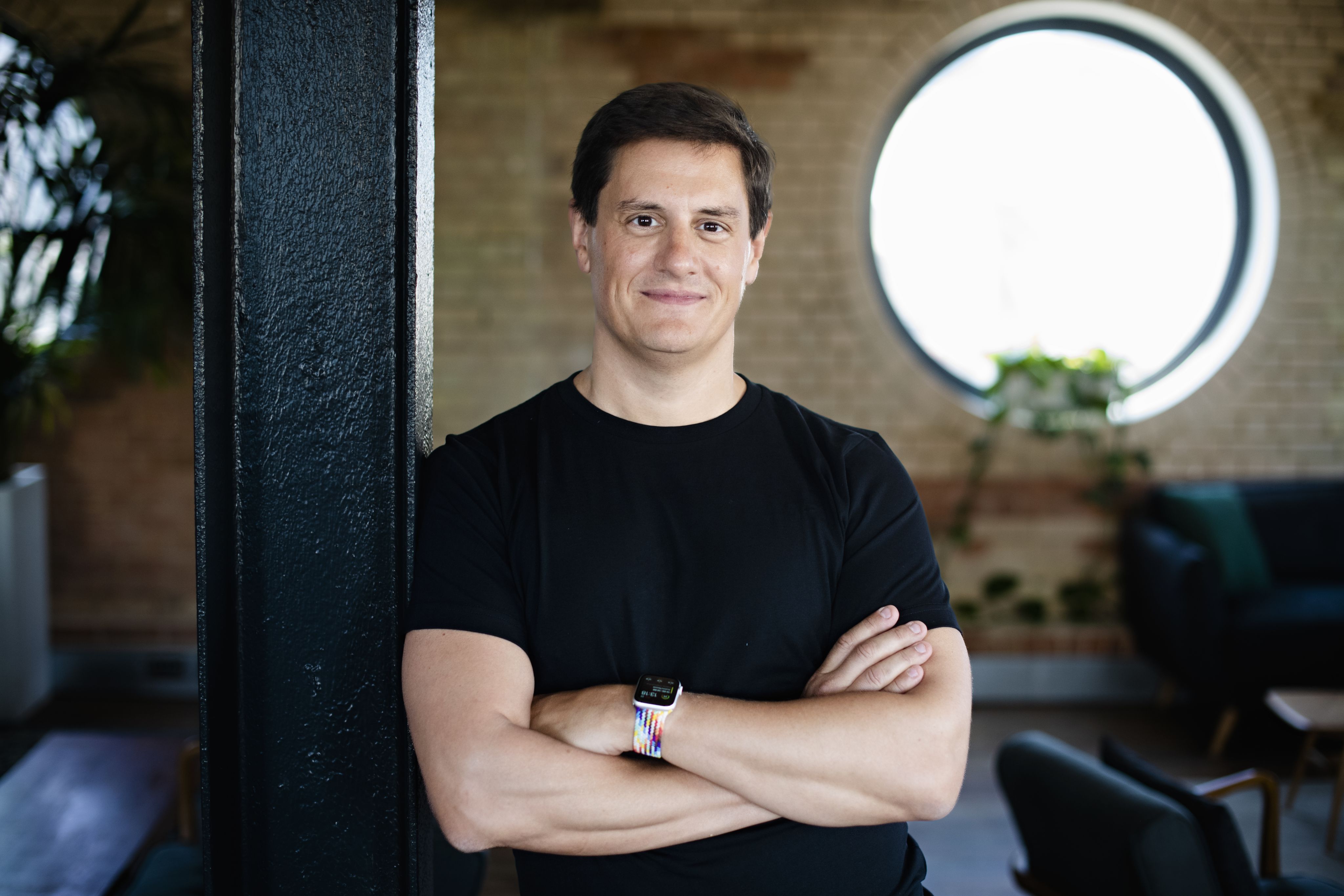 Justin Basini, CEO and Co-Founder of ClearScore, leans against a post with his arms crossed.smith as Cressida gestures on stage.