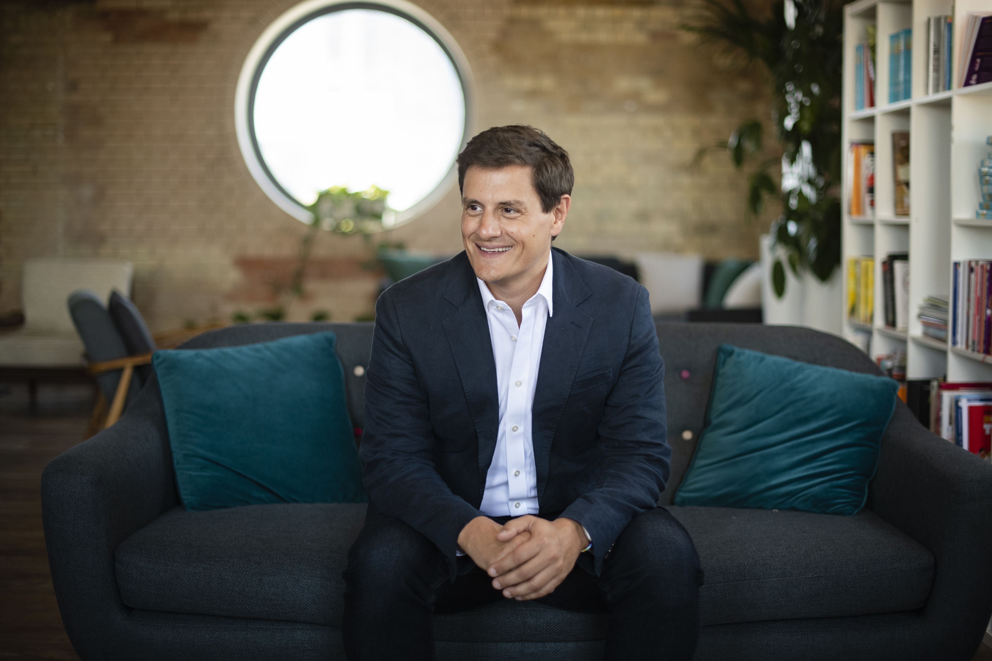 Justin Basini, CEO and Co-Founder of ClearScore, sits on a sofa smiling.