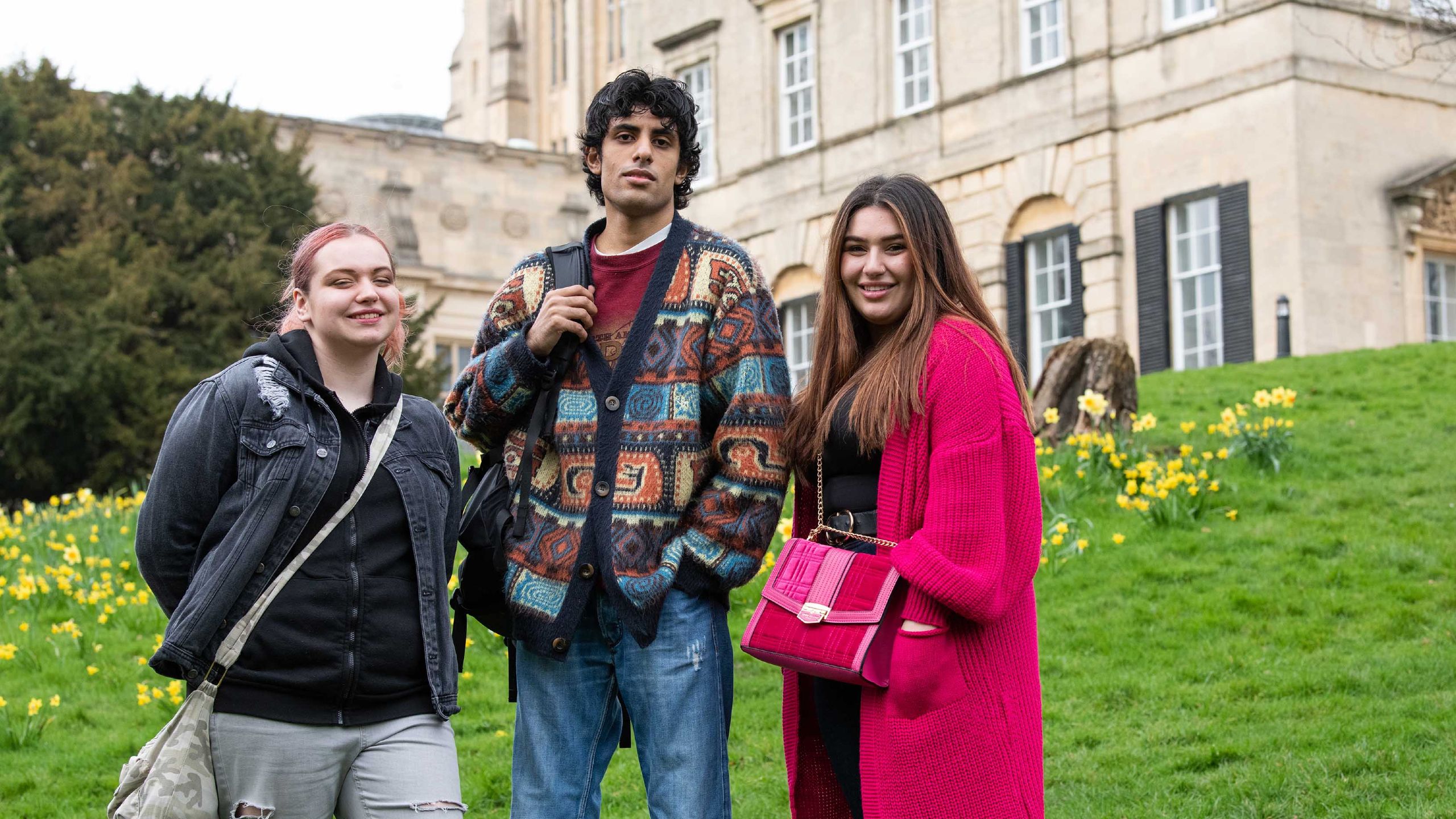 Three Futures Scholars pose together on the green lawn of Royal Fort Gardens smiling.