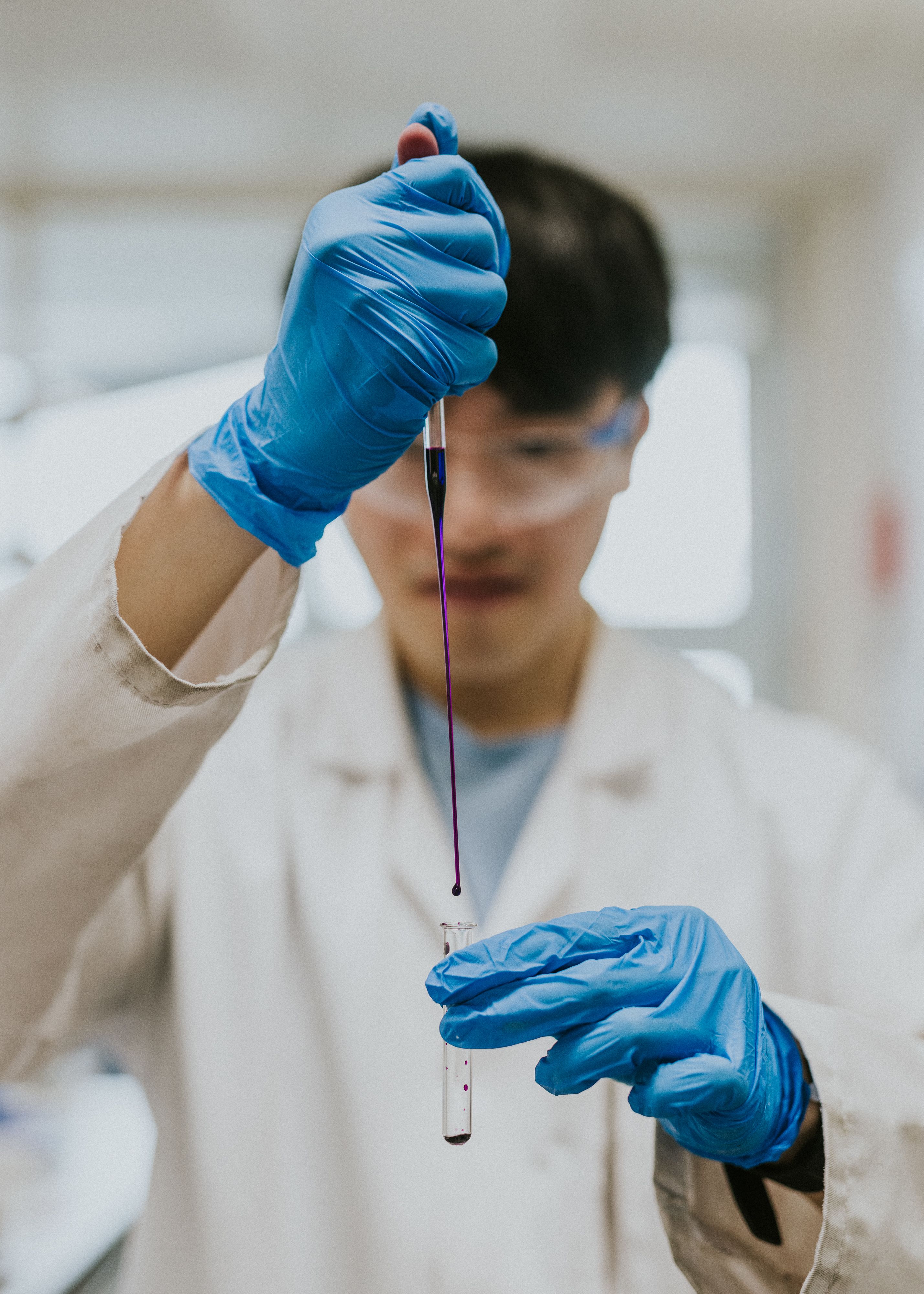 bioengineering scientist in lab coat transferring liquid from pipette into test tube