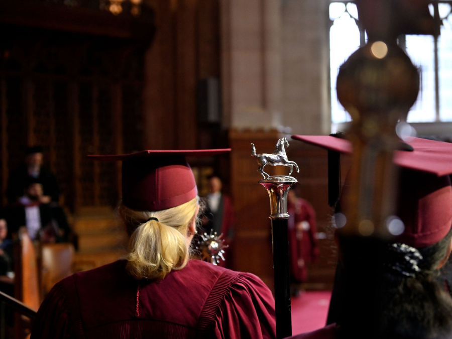 A member of the graduation procession watching the ceremony.