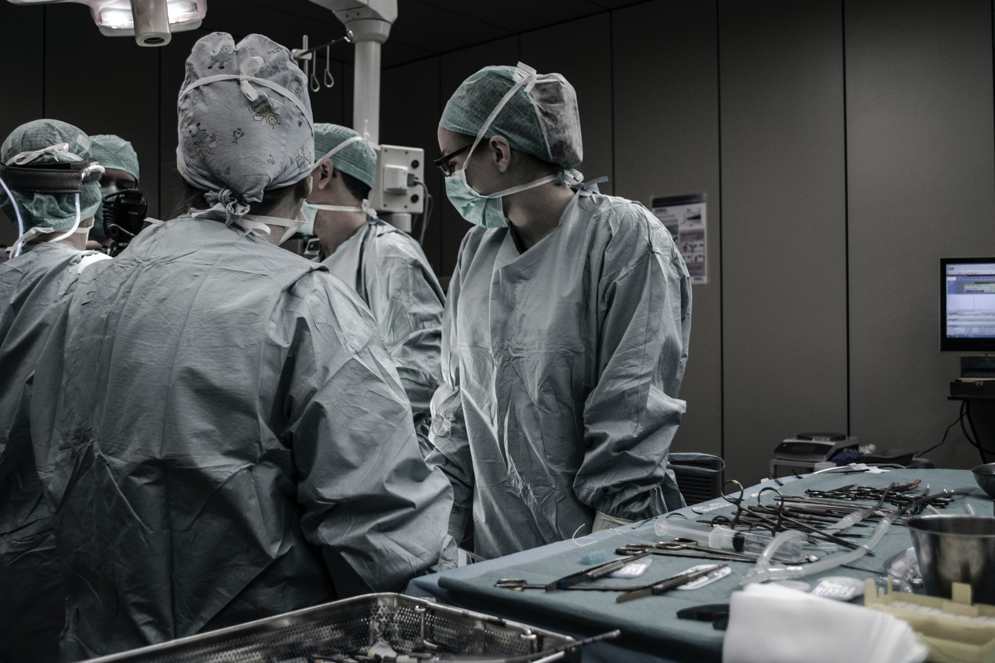 Surgeons preparing for theatre, wearing scrubs with medical equipment next to them