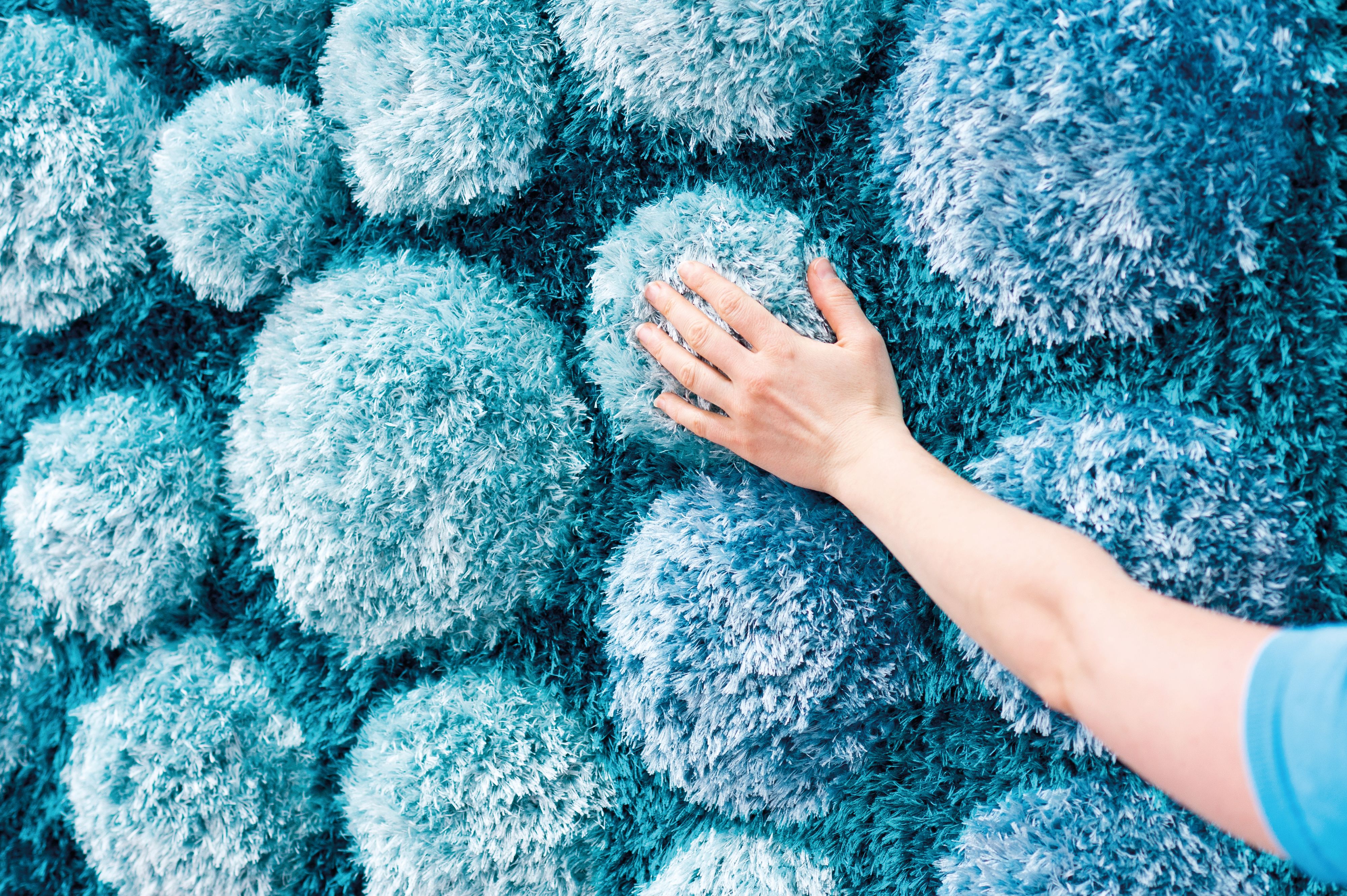 On the bottom right hand corner, an arm is outstretched to touch a collection of blue fluffy objects